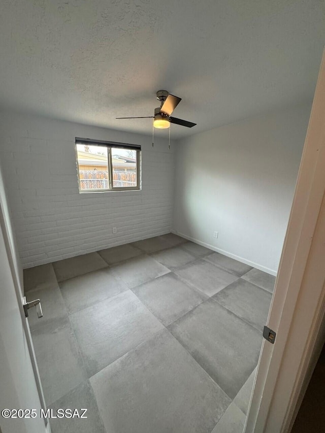 516 E Linden St, Tucson, AZ 85705 - unfurnished room featuring ceiling fan, brick wall, a textured ceiling, and baseboards