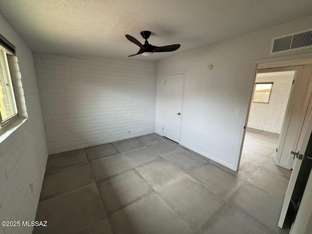 516 E Linden St, Tucson, AZ 85705 - unfurnished bedroom featuring brick wall, a textured ceiling, and a ceiling fan
