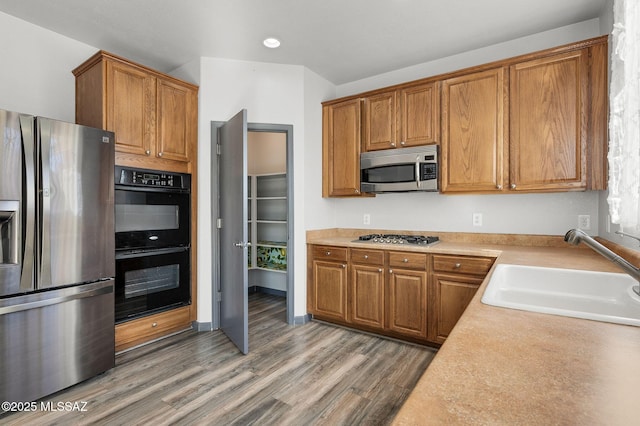 329 W Vuelta Friso, Sahuarita, AZ 85629 - kitchen with appliances with stainless steel finishes, a sink, light wood-style floors, and brown cabinetry