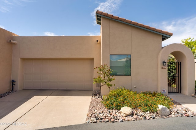 6061 N Tocito Pl, Tucson, AZ 85718 - pueblo-style home featuring stucco siding, driveway, an attached garage, and a gate