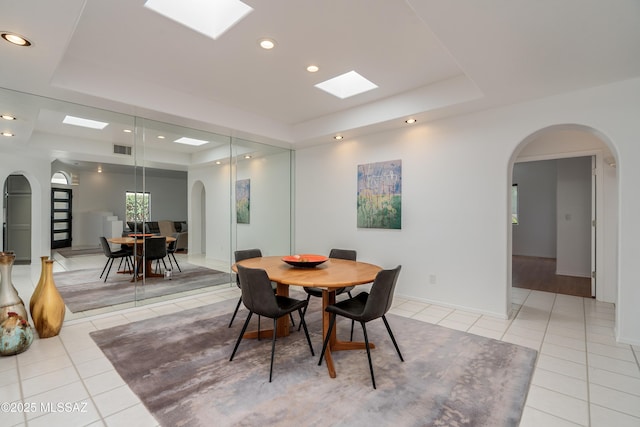 6061 N Tocito Pl, Tucson, AZ 85718 - dining space with a tray ceiling, light tile patterned floors, arched walkways, a skylight, and recessed lighting