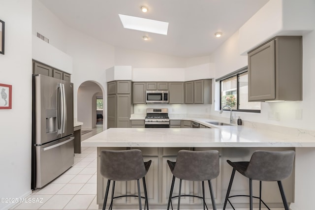 6061 N Tocito Pl, Tucson, AZ 85718 - kitchen featuring stainless steel appliances, a sink, gray cabinetry, a peninsula, and a skylight