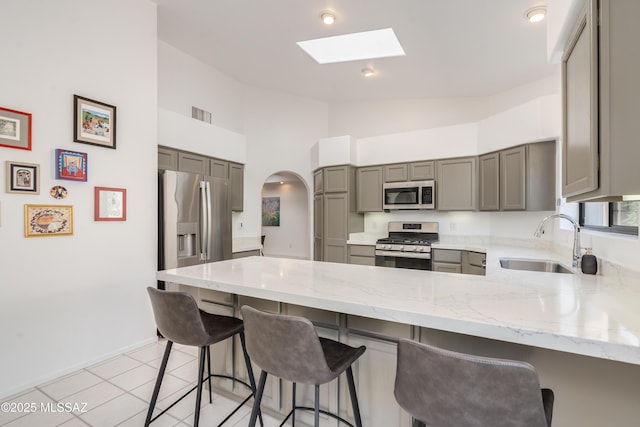 6061 N Tocito Pl, Tucson, AZ 85718 - kitchen with stainless steel appliances, gray cabinets, a sink, a peninsula, and light stone counters