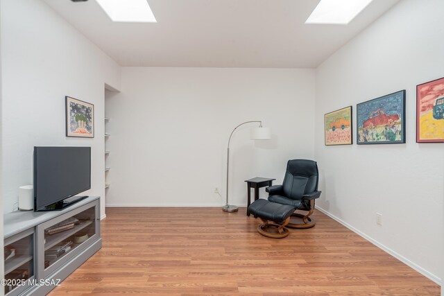 6061 N Tocito Pl, Tucson, AZ 85718 - sitting room featuring a skylight, light wood-style floors, and baseboards