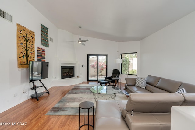 6061 N Tocito Pl, Tucson, AZ 85718 - living room featuring a ceiling fan, light wood finished floors, a glass covered fireplace, and lofted ceiling