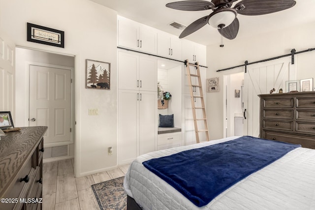5831 N Moonbrook Rd, Tucson, AZ 85741 - bedroom with a barn door, light wood finished floors, a closet, baseboards, and ceiling fan