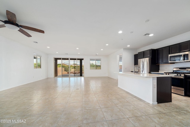 11324 Granite Gulch Way, Tucson, AZ 85747 - kitchen featuring appliances with stainless steel finishes, open floor plan, light countertops, a kitchen island with sink, and dark cabinets