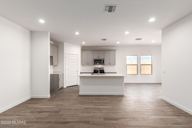 9810 E Gray Hawk Dr, Tucson, AZ 85730 - kitchen featuring stainless steel microwave, gray cabinets, dark wood-type flooring, recessed lighting, and a kitchen island with sink