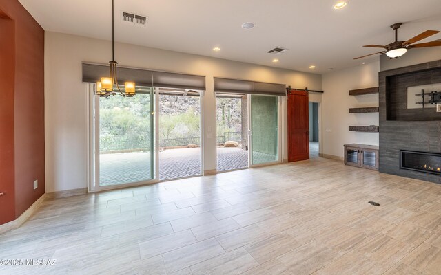 13570 N Nightstar Ct, Marana, AZ 85658 - unfurnished living room with a ceiling fan, a barn door, recessed lighting, a large fireplace, and a chandelier