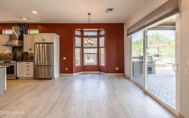 13570 N Nightstar Ct, Marana, AZ 85658 - kitchen with appliances with stainless steel finishes, wall chimney range hood, a chandelier, decorative light fixtures, and light wood-style flooring