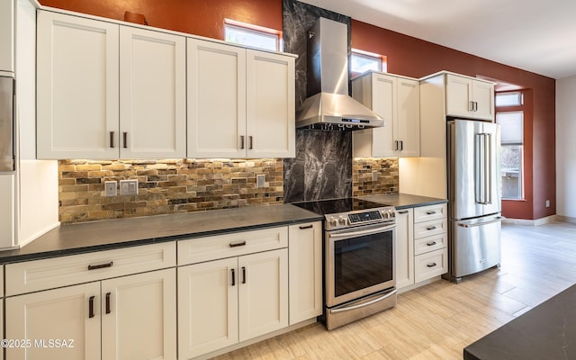 13570 N Nightstar Ct, Marana, AZ 85658 - kitchen with appliances with stainless steel finishes, wall chimney range hood, dark countertops, tasteful backsplash, and light wood-type flooring