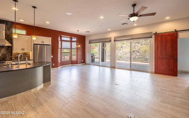 13570 N Nightstar Ct, Marana, AZ 85658 - unfurnished living room featuring ceiling fan, recessed lighting, a barn door, baseboards, and a sink