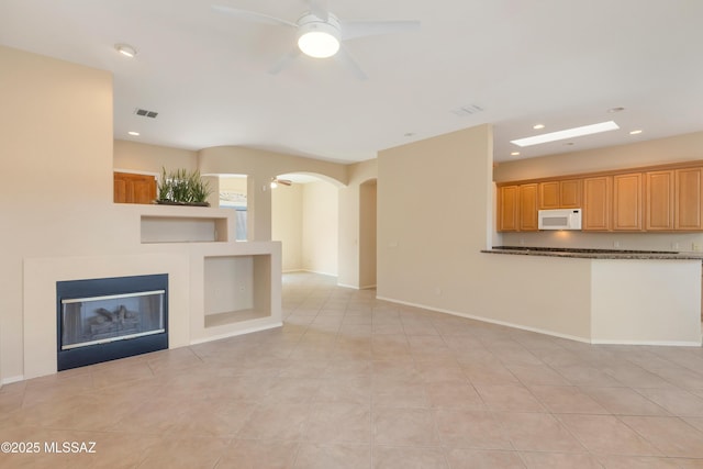 6321 N Via Lomas De Paloma, Tucson, AZ 85718 - unfurnished living room featuring arched walkways, ceiling fan, recessed lighting, a glass covered fireplace, and light tile patterned floors
