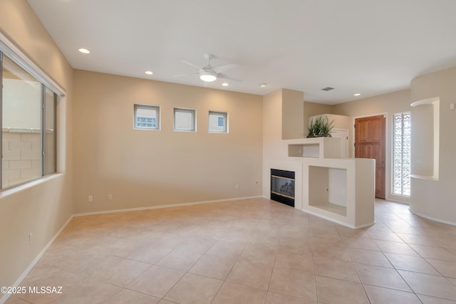 6321 N Via Lomas De Paloma, Tucson, AZ 85718 - unfurnished living room featuring a glass covered fireplace, ceiling fan, light tile patterned floors, recessed lighting, and baseboards