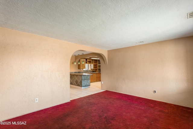 908 E Weymouth St, Tucson, AZ 85719 - unfurnished room with arched walkways, light carpet, a textured ceiling, and a textured wall
