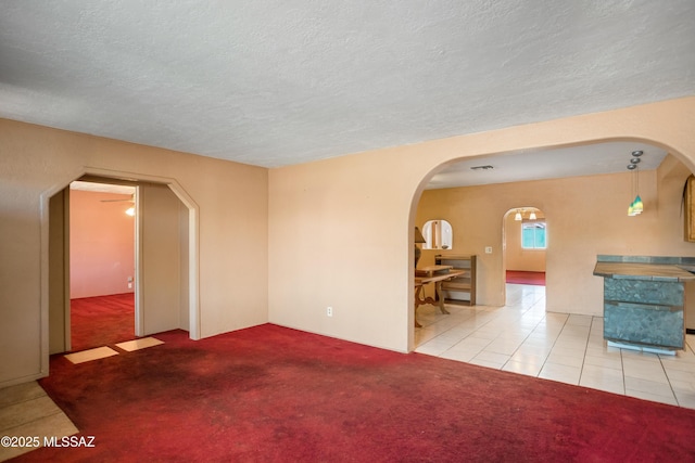 908 E Weymouth St, Tucson, AZ 85719 - unfurnished room featuring arched walkways, a textured ceiling, carpet, and tile patterned flooring