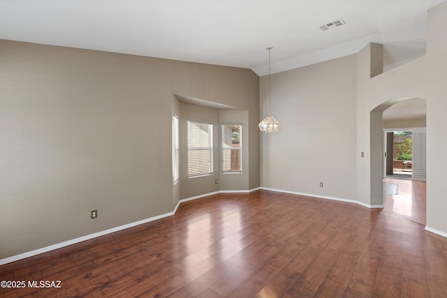 9510 E Danforth Pl, Tucson, AZ 85747 - spare room with arched walkways, dark wood-type flooring, baseboards, high vaulted ceiling, and a chandelier