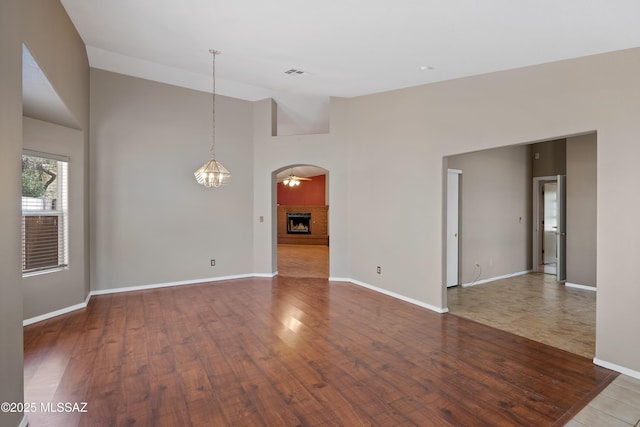 9510 E Danforth Pl, Tucson, AZ 85747 - unfurnished room featuring baseboards, a fireplace, wood finished floors, and high vaulted ceiling