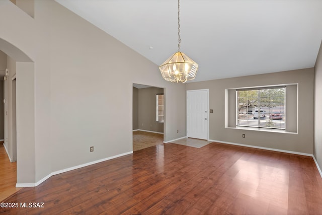 9510 E Danforth Pl, Tucson, AZ 85747 - unfurnished room with a chandelier, arched walkways, wood finished floors, baseboards, and high vaulted ceiling
