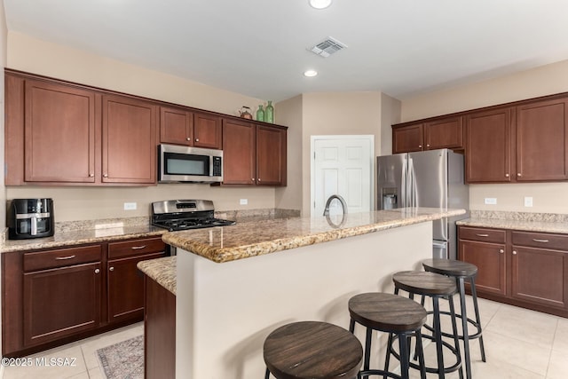 102 E Forrest Feezor St, Vail, AZ 85641 - kitchen with appliances with stainless steel finishes, light tile patterned floors, a breakfast bar area, a kitchen island with sink, and light stone counters