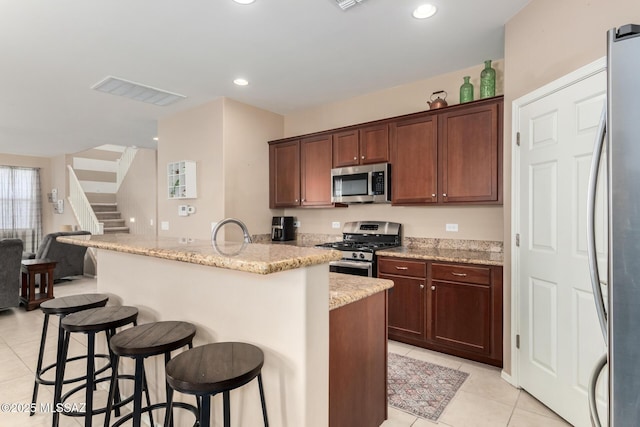 102 E Forrest Feezor St, Vail, AZ 85641 - kitchen with stainless steel appliances, light tile patterned floors, a kitchen breakfast bar, light stone countertops, and open floor plan