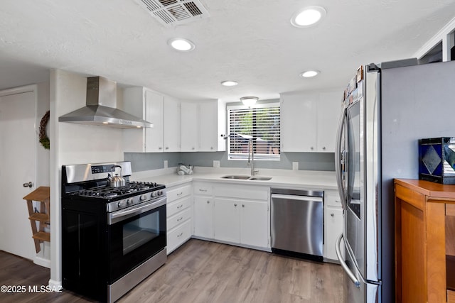 745 N Las Flores Dr, Oracle, AZ 85623 - kitchen featuring appliances with stainless steel finishes, wall chimney exhaust hood, light countertops, light wood-style flooring, and white cabinets