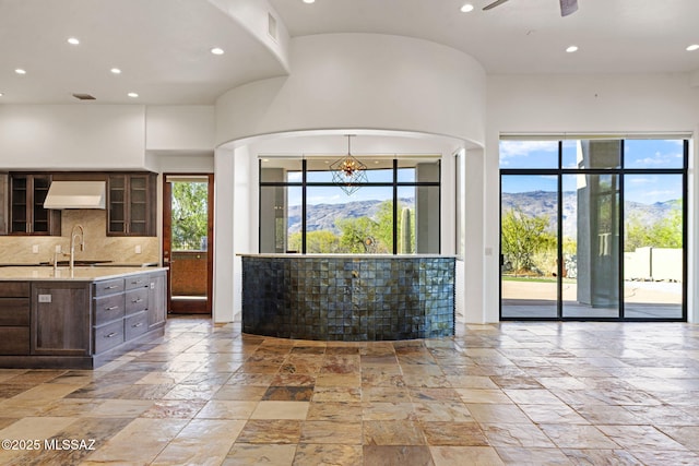8505 S Circle C Ranch Rd, Vail, AZ 85641 - kitchen featuring stone tile floors, custom range hood, dark brown cabinetry, glass insert cabinets, and recessed lighting