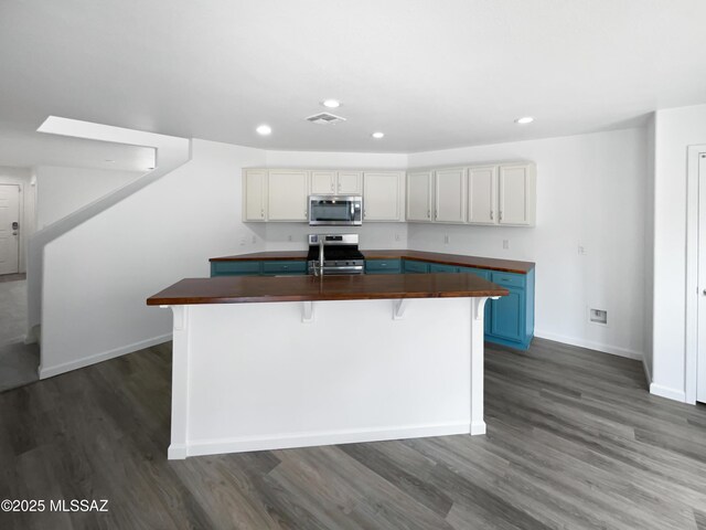 7637 E Cholla Overlook Dr, Tucson, AZ 85710 - kitchen featuring appliances with stainless steel finishes, dark wood-style flooring, recessed lighting, a kitchen island with sink, and baseboards