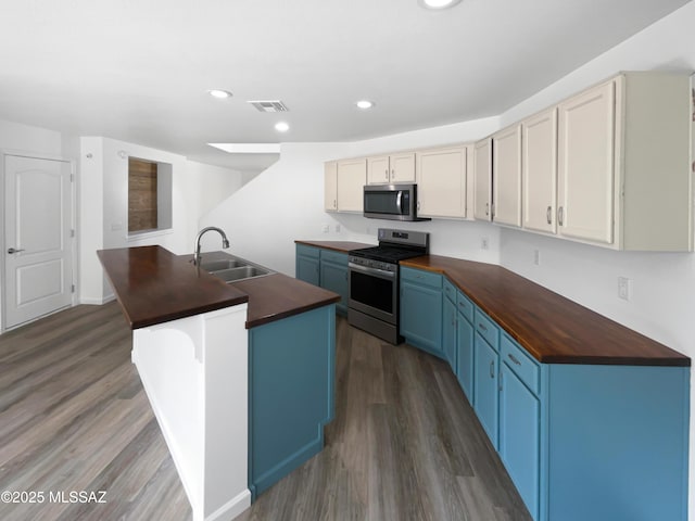 7637 E Cholla Overlook Dr, Tucson, AZ 85710 - kitchen with wood counters, stainless steel appliances, a sink, blue cabinetry, and wood finished floors