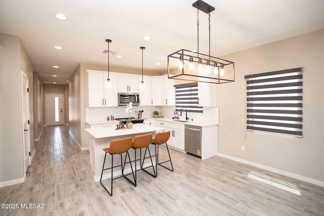 3601 E Nebraska Stra, Tucson, AZ 85706 - kitchen featuring stainless steel appliances, light countertops, white cabinetry, a kitchen island, and a kitchen breakfast bar