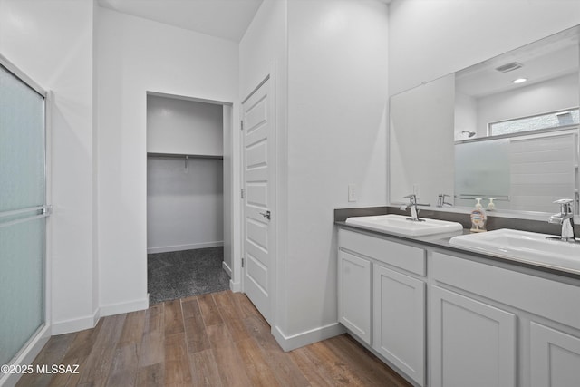12767 E Giada Dr, Vail, AZ 85641 - full bathroom featuring an enclosed shower, double vanity, wood finished floors, a walk in closet, and baseboards