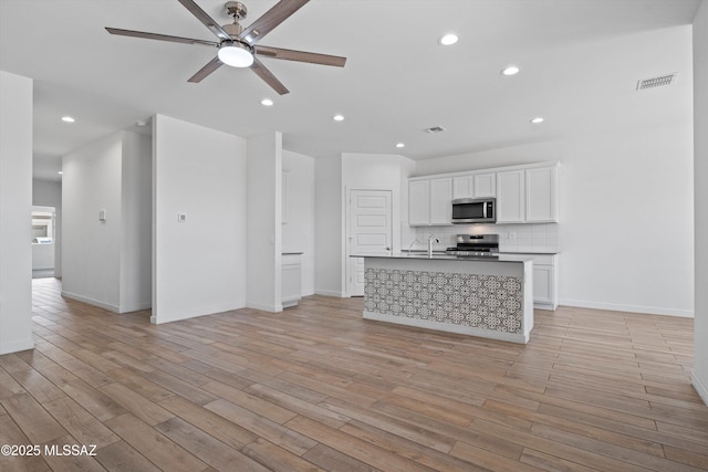12767 E Giada Dr, Vail, AZ 85641 - unfurnished living room featuring ceiling fan, light wood-style flooring, recessed lighting, baseboards, and a sink