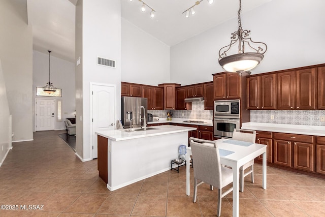 7397 W Crimson Ridge Dr, Marana, AZ 85743 - kitchen with appliances with stainless steel finishes, high vaulted ceiling, under cabinet range hood, tasteful backsplash, and light countertops