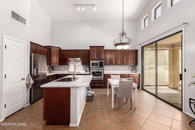 7397 W Crimson Ridge Dr, Marana, AZ 85743 - kitchen with appliances with stainless steel finishes, a towering ceiling, light countertops, light tile patterned flooring, and backsplash