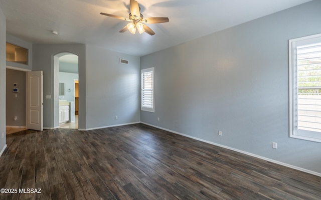 8892 N Silver Moon Way, Tucson, AZ 85743 - empty room with arched walkways, a ceiling fan, dark wood finished floors, and healthy amount of natural light