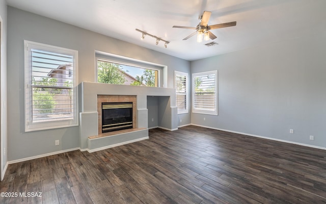 8892 N Silver Moon Way, Tucson, AZ 85743 - unfurnished living room featuring a tile fireplace, ceiling fan, dark wood-style floors, and baseboards