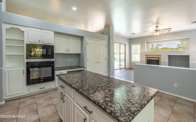 8892 N Silver Moon Way, Tucson, AZ 85743 - kitchen with black appliances, ceiling fan, a glass covered fireplace, a kitchen island, and dark stone counters