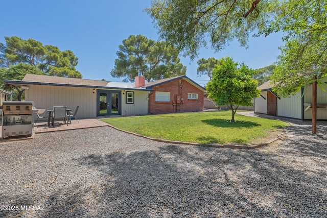 3357 N Christmas Ave, Tucson, AZ 85716 - back of property featuring french doors, a chimney, a lawn, a patio, and an outdoor structure