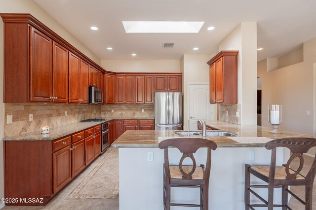 3259 E Corte Doce Palomas, Tucson, AZ 85718 - kitchen with stainless steel appliances, a sink, a peninsula, a skylight, and a kitchen bar
