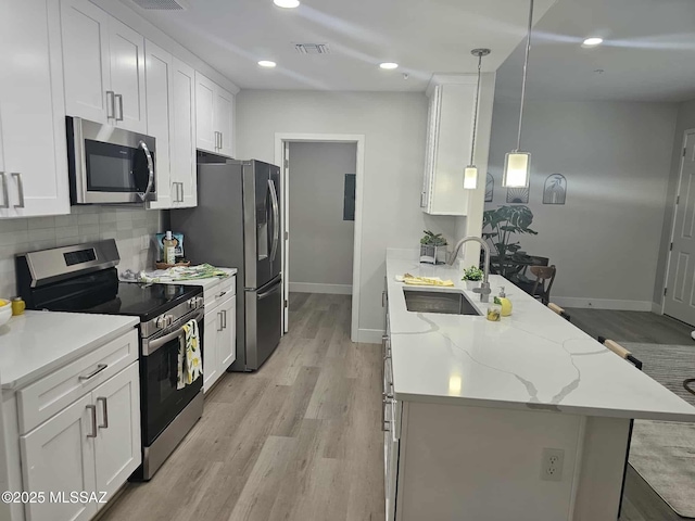 2020 E River Rd Unit 205, Tucson, AZ 85718 - kitchen featuring appliances with stainless steel finishes, a peninsula, a sink, baseboards, and light wood finished floors