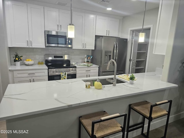 2020 E River Rd Unit 205, Tucson, AZ 85718 - kitchen featuring stainless steel appliances, tasteful backsplash, white cabinets, light stone countertops, and decorative light fixtures