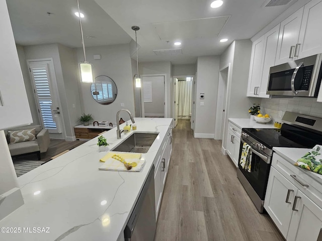 2020 E River Rd Unit 205, Tucson, AZ 85718 - kitchen with stainless steel appliances, a sink, light wood-style floors, backsplash, and white cabinets