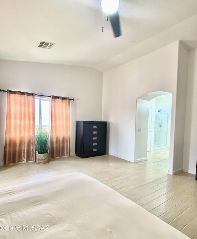 9828 N Niobrara Way, Tucson, AZ 85742 - unfurnished bedroom featuring arched walkways, light wood-type flooring, a ceiling fan, and baseboards