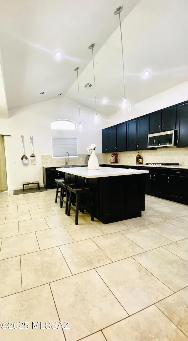 9828 N Niobrara Way, Tucson, AZ 85742 - kitchen featuring dark cabinets, stainless steel microwave, backsplash, light countertops, and lofted ceiling