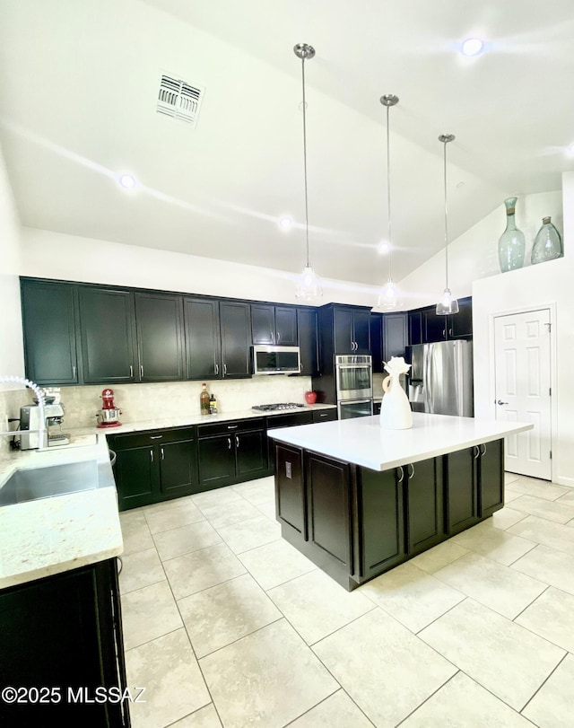 9828 N Niobrara Way, Tucson, AZ 85742 - kitchen featuring appliances with stainless steel finishes, tasteful backsplash, a sink, light tile patterned floors, and a center island