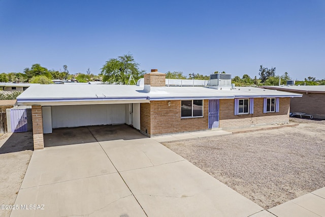 7821 N Jensen Dr, Tucson, AZ 85741 - view of front of house featuring driveway, brick siding, a chimney, and a carport