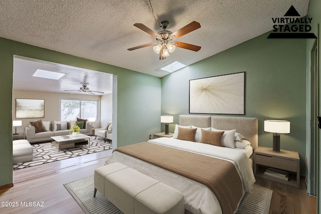 7821 N Jensen Dr, Tucson, AZ 85741 - bedroom featuring a skylight, vaulted ceiling, wood finished floors, a textured ceiling, and ceiling fan