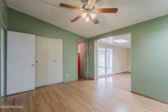 7821 N Jensen Dr, Tucson, AZ 85741 - unfurnished bedroom with lofted ceiling, wood finished floors, a skylight, a textured ceiling, and a closet