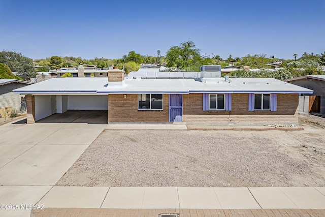 7821 N Jensen Dr, Tucson, AZ 85741 - view of front of home with a carport, concrete driveway, brick siding, and a chimney