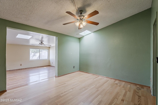 7821 N Jensen Dr, Tucson, AZ 85741 - unfurnished room with a skylight, light wood-type flooring, a ceiling fan, a textured ceiling, and a textured wall